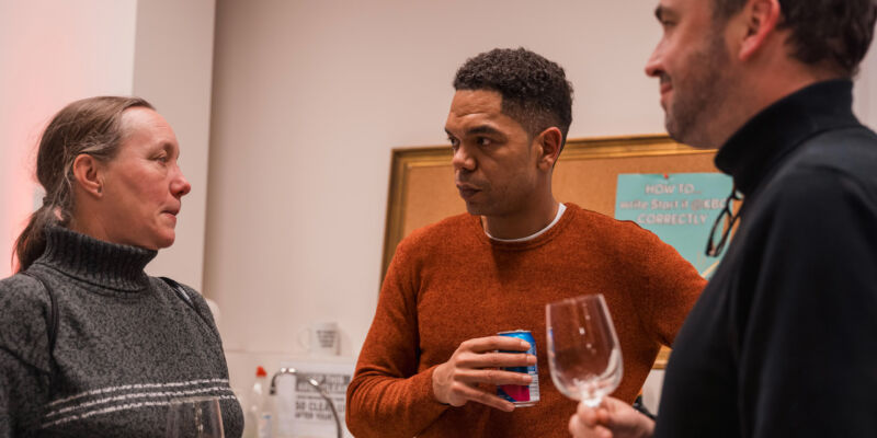 Coworkers having a casual conversation with drinks in a shared kitchen area