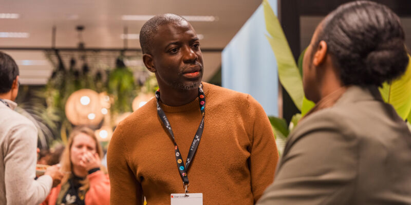 Man with lanyard talking to a fellow entrepreneur at a networking event in Brussels